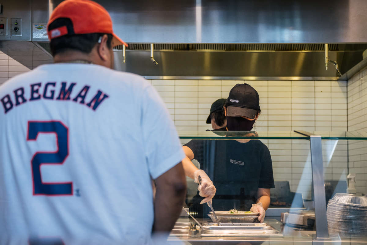 A Chipotle worker serves a man in line on June 9, 2021, in Houston, Texas. Chipotle Mexican Grill reported massive pay gaps last year, according to a new analysis.