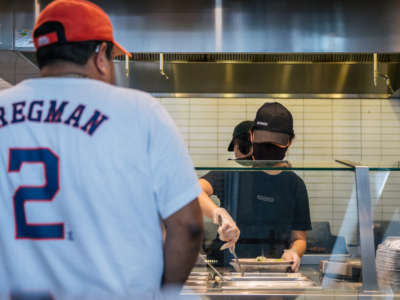 A Chipotle worker serves a man in line on June 9, 2021, in Houston, Texas. Chipotle Mexican Grill reported massive pay gaps last year, according to a new analysis.