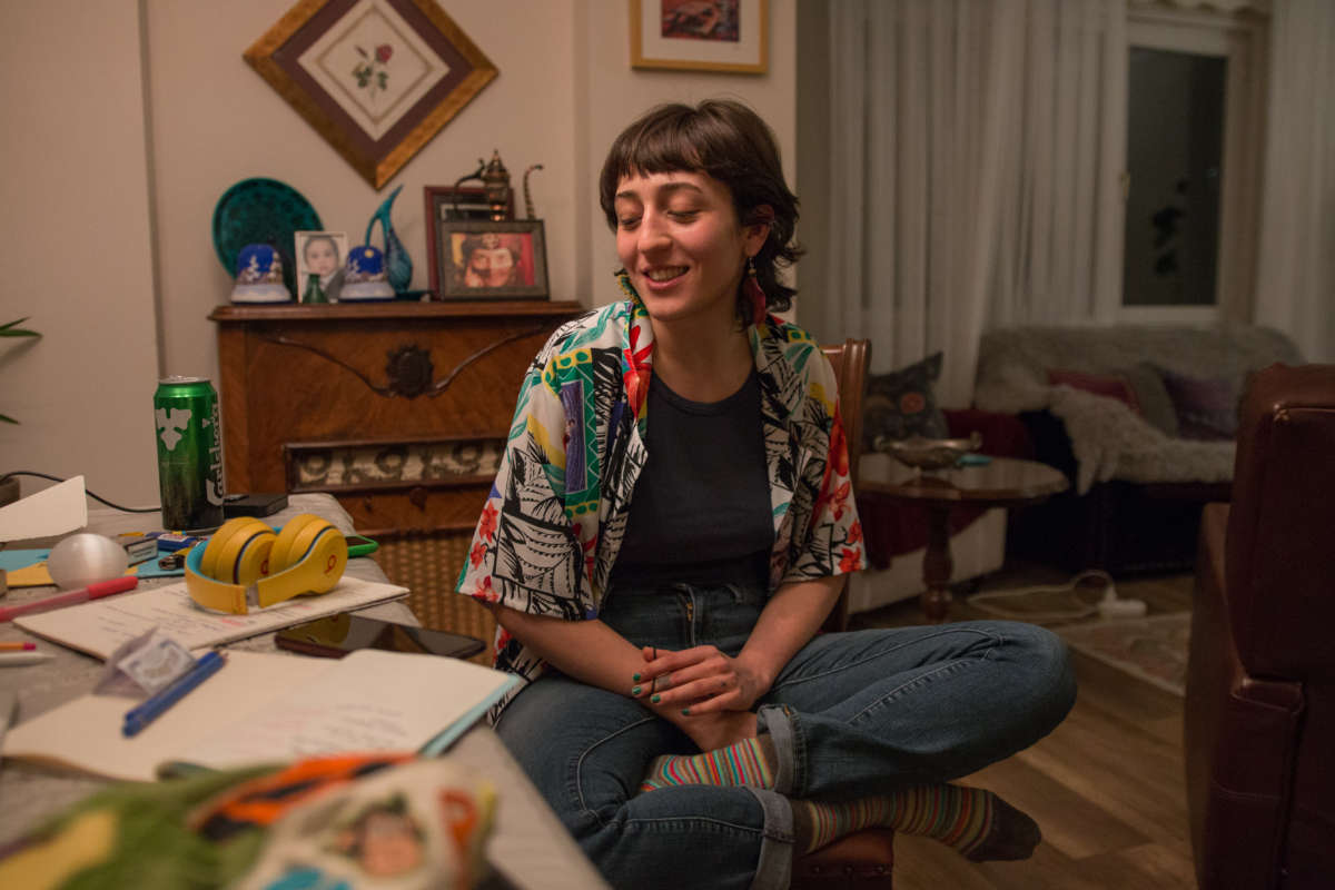 Hazar Kolancalı sits in the living room at the table where she works.