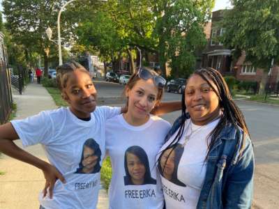 Three women pose for a photo while wearing matching shirts, each bearing Erika Ray's face with the message "FREE ERIKA" written below it.