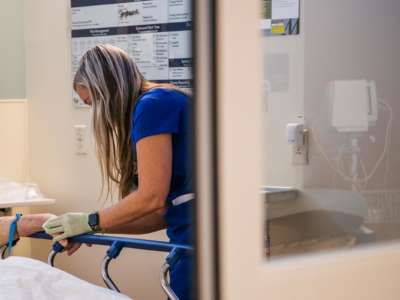 A nurse tends to a patient at their bedside