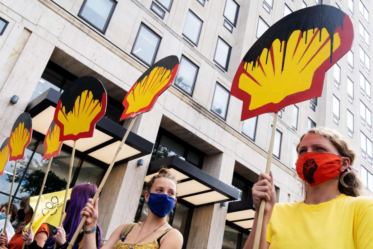 Protesters hold signs resembling the Shell logo dripping with oil