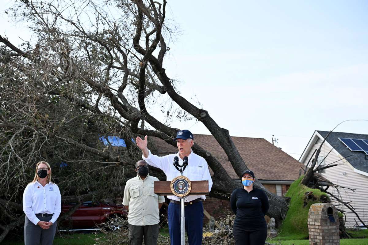 Joe Biden speaks in front of a home with a downed tree laying across its roof