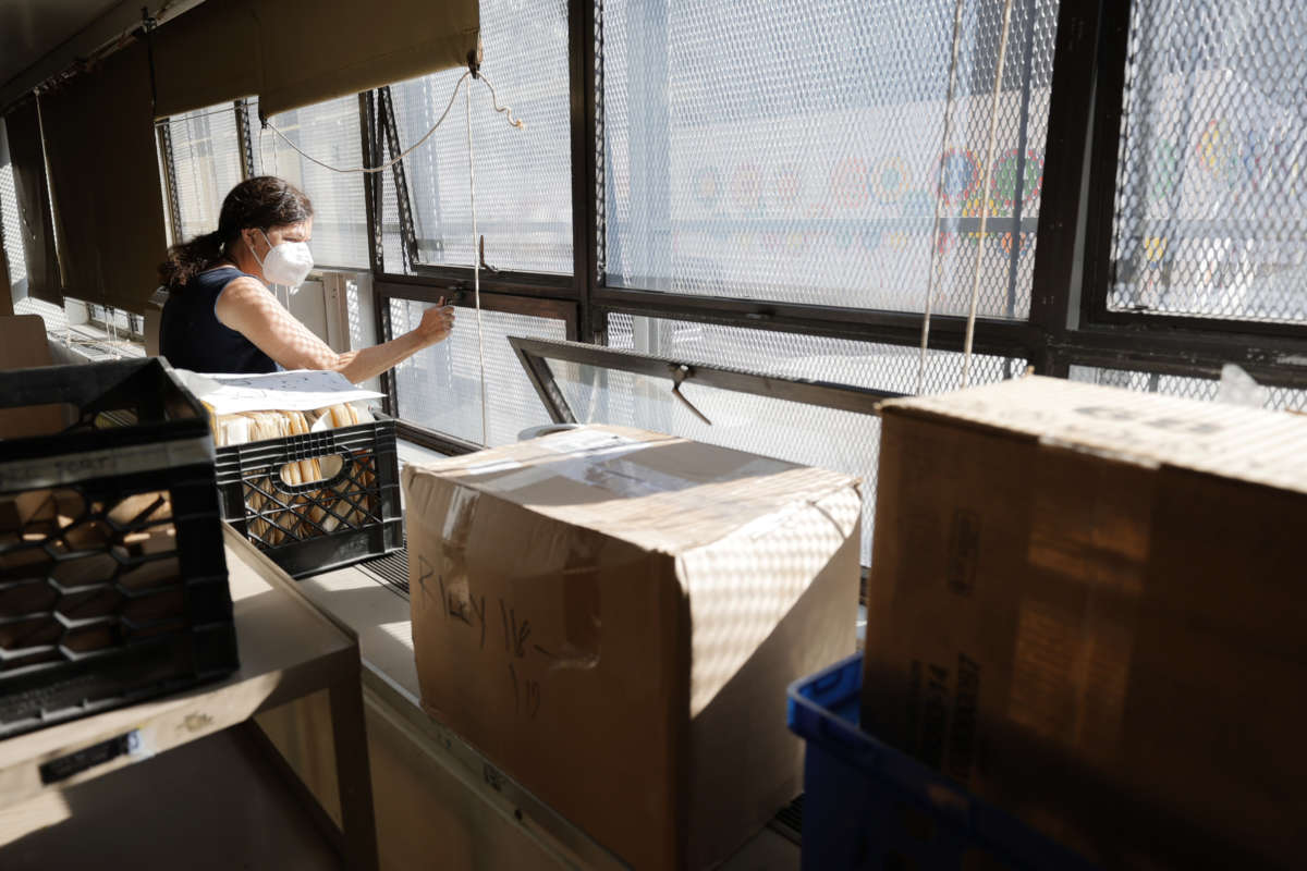 A masked teacher cleans the windows of her classroom