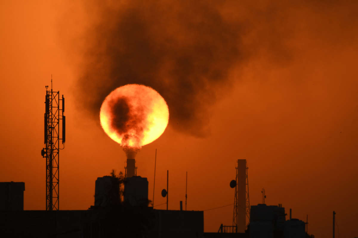 The sun sets behind an oil refinery