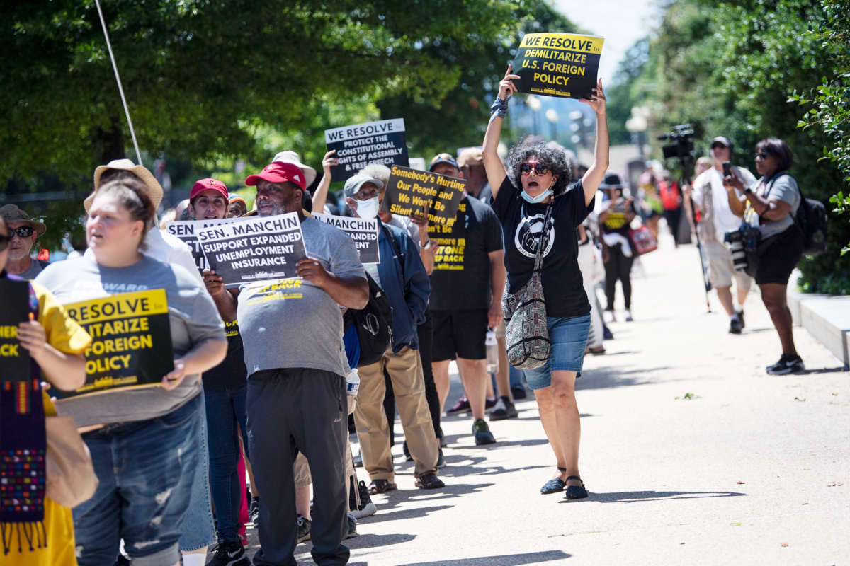 Demonstrators display signs calling on congress to demilitarize