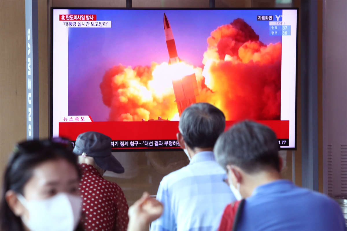 People are seen watching television footage of a missile launch
