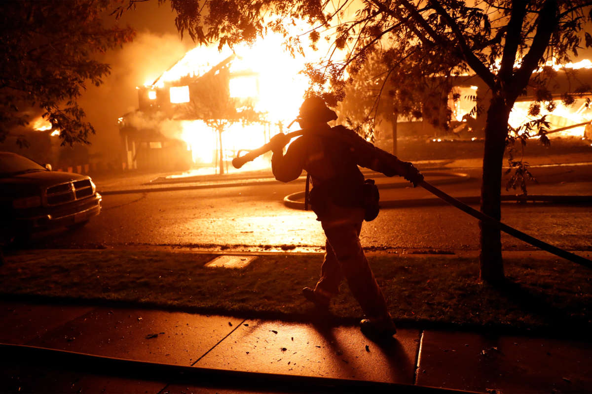 A firefighter moves a hose while trying to save houses on Mountain Hawk Drive as the Shady Fire burns in the Skyhawk area of Santa Rosa, California, on September 28, 2020.