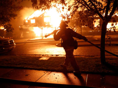 A firefighter moves a hose while trying to save houses on Mountain Hawk Drive as the Shady Fire burns in the Skyhawk area of Santa Rosa, California, on September 28, 2020.