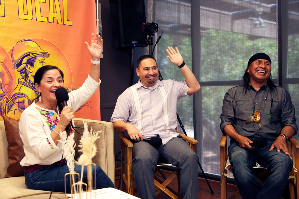 Isela Blanc and Martin Quezada smile and raise their hands during an interview as Wendsler Nosie Sr. laughs beside them