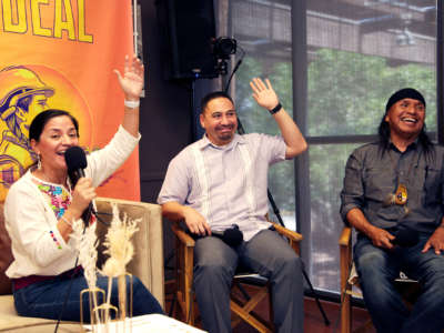 Isela Blanc and Martin Quezada smile and raise their hands during an interview as Wendsler Nosie Sr. laughs beside them
