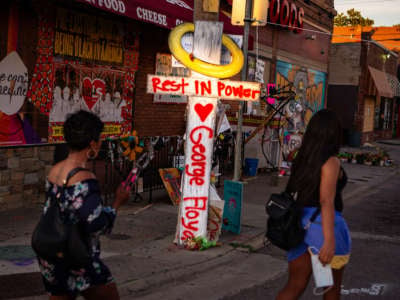 Two months after the Minneapolis upraising visitors continue to pay their respects at George Floyd's makeshift memorial as fleeting rays of sunlight illuminate a haloed cross inscribed with the words "Rest in Power George Floyd" on July 26, 2020, in Minneapolis, MN.