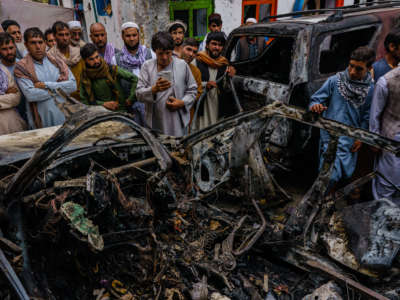 Relatives and neighbors of the Ahmadi family gathered around the incinerated husk of a vehicle targeted and hit earlier Sunday afternoon by a U.S. drone strike, in Kabul, Afghanistan, on August 30, 2021.