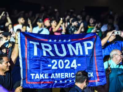 Supporters of former President Donald Trump hold a flag as he hosts the Holyfield vs. Belford boxing match live with commentary at the Hard Rock Live in Hollywood, Florida on September 11, 2021.