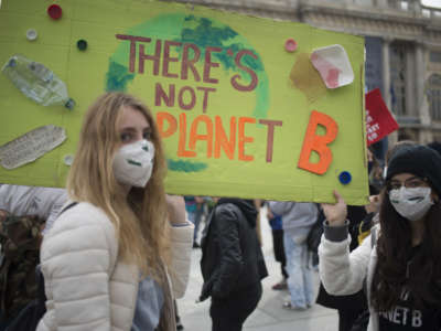 Two climate strikers wear protective mask holds protest signs during a protest as part of the Fridays for Future movement to call for action against climate change on October 9, 2020, in Turin, Italy.