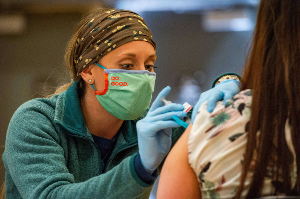 A medical worker administer a COVID-19 vaccine to the public at a FEMA-run mobile clinic at Biddeford High School in Bidderford, Maine, on April 26, 2021.