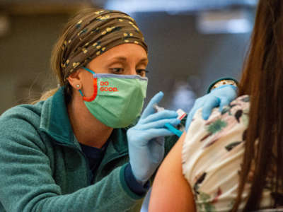 A medical worker administer a COVID-19 vaccine to the public at a FEMA-run mobile clinic at Biddeford High School in Bidderford, Maine, on April 26, 2021.