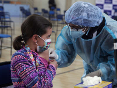 A healthcare worker administers the first dose of a Pfizer vaccine as part of the immunization plan against COVID-19 for children aged 5-to-11 on October 18, 2021, in Cuenca, Ecuador.