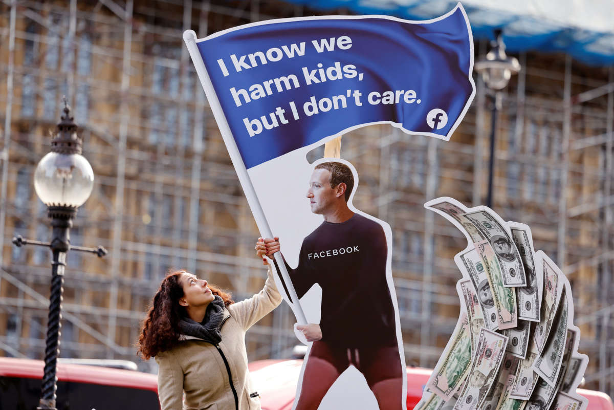 an art installation of mark zuckerberg holding a flag reading "I know we harm kids, but I don't care" as a wave of cash swells behind him