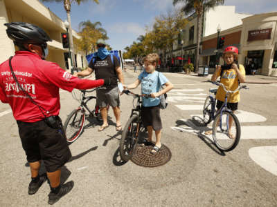A "Safety Ambassador" with the Downtown Ventura Partners Improvement District hands out a free face mask on August 11, 2020, in Los Angeles, CA.