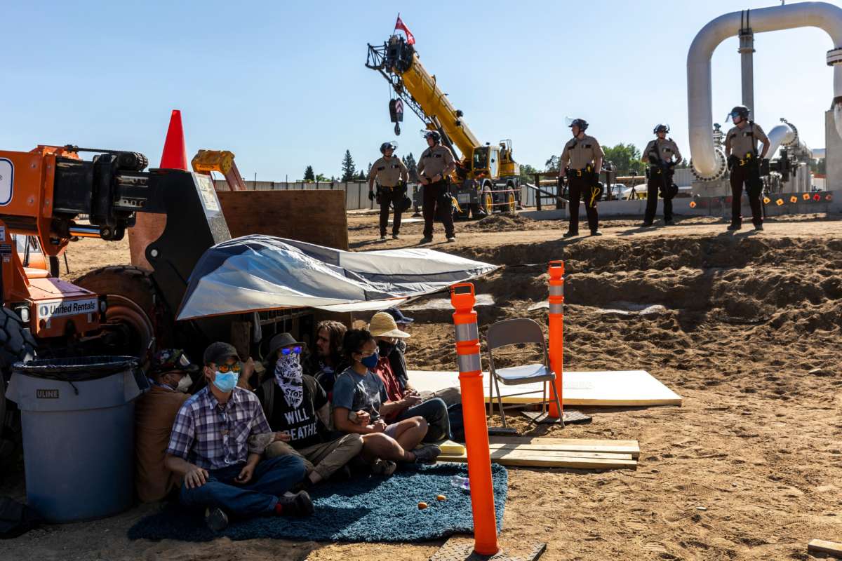 Water Protectors lock down to construction equipment at a Line 3 pipeline pumping station near the Itasca State Park in Minnesota as police in riot gear line up, on June 7, 2021.