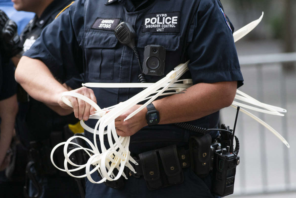 A NYPD officer gets zip ties ready to handcuff protesters during a "Defund the Police" protest outside the Metropolitan Museum of Art during the MET Gala in New York City, on September 13, 2021.