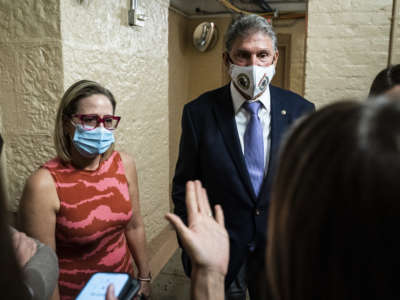 Sen. Kyrsten Sinema and Sen. Joe Manchin speak to a reporter after a private meeting between the two of them before a vote on Capitol Hill on September 30, 2021, in Washington, D.C.