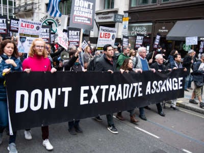 Протестующие держат плакаты и транспаранты во время марша от BBC к Королевскому двору в поддержку Джулиана Ассанжа 23 октября 2021 года в Лондоне, Англия.