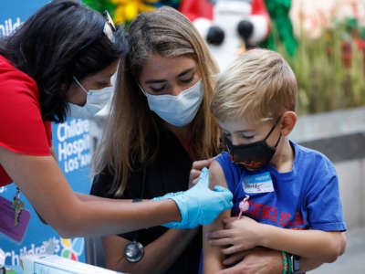 A 6-year-old is held by his mother as a nursing professional development manager administers the children's dose of the Pfizer COVID vaccine at Children's Hospital of Los Angeles on November 3, 2021, in Los Angeles, California.