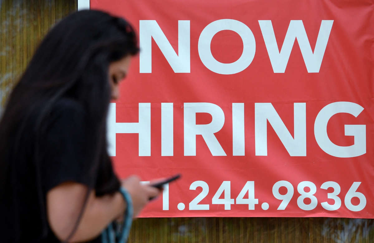 A woman walks by a "Now Hiring" sign outside a store on August 16, 2021, in Arlington, Virginia.