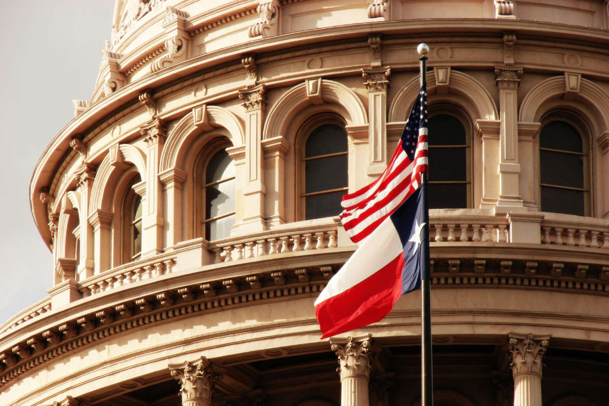 The Texas state capitol building with USA and Texas flags