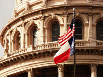 The Texas state capitol building with USA and Texas flags