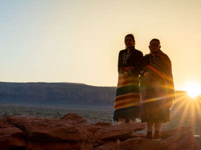 Two Teenage Native American Indigenous Navajo Sister in Traditional Clothing Enjoying the Vast Desert and Red Rock Landscape in the Famous Navajo Tribal Park in Monument Valley Arizona at Dawn