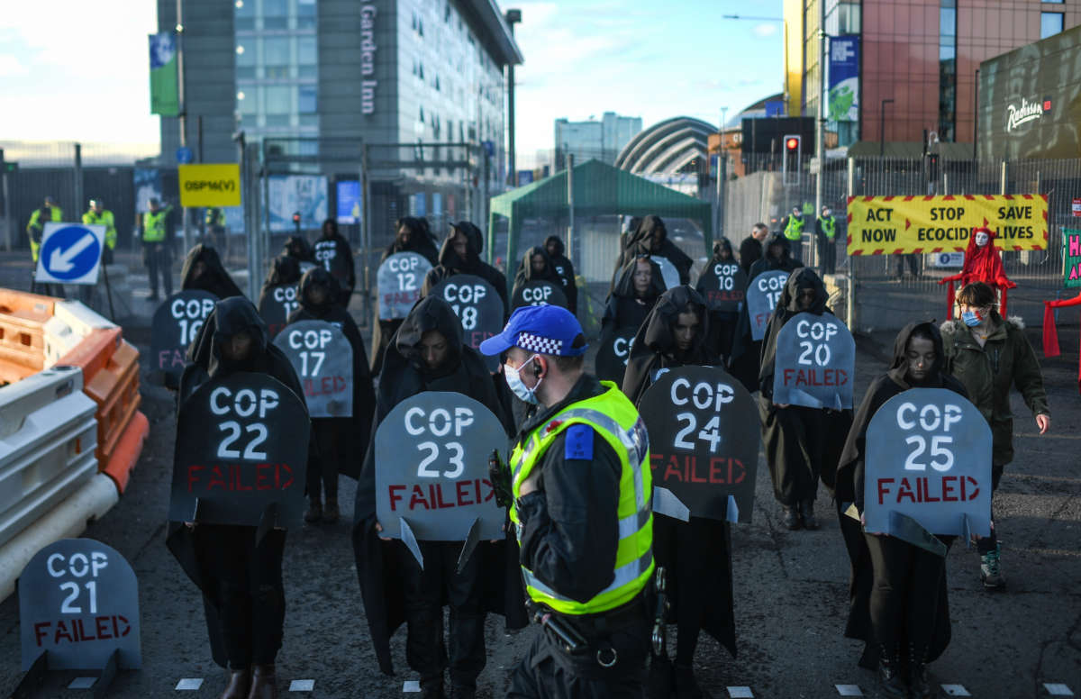 A police officer walks past Extinction Rebellion protesters during a die-in protest outside the entrance to the COP26 site on November 13, 2021, in Glasgow, United Kingdom.