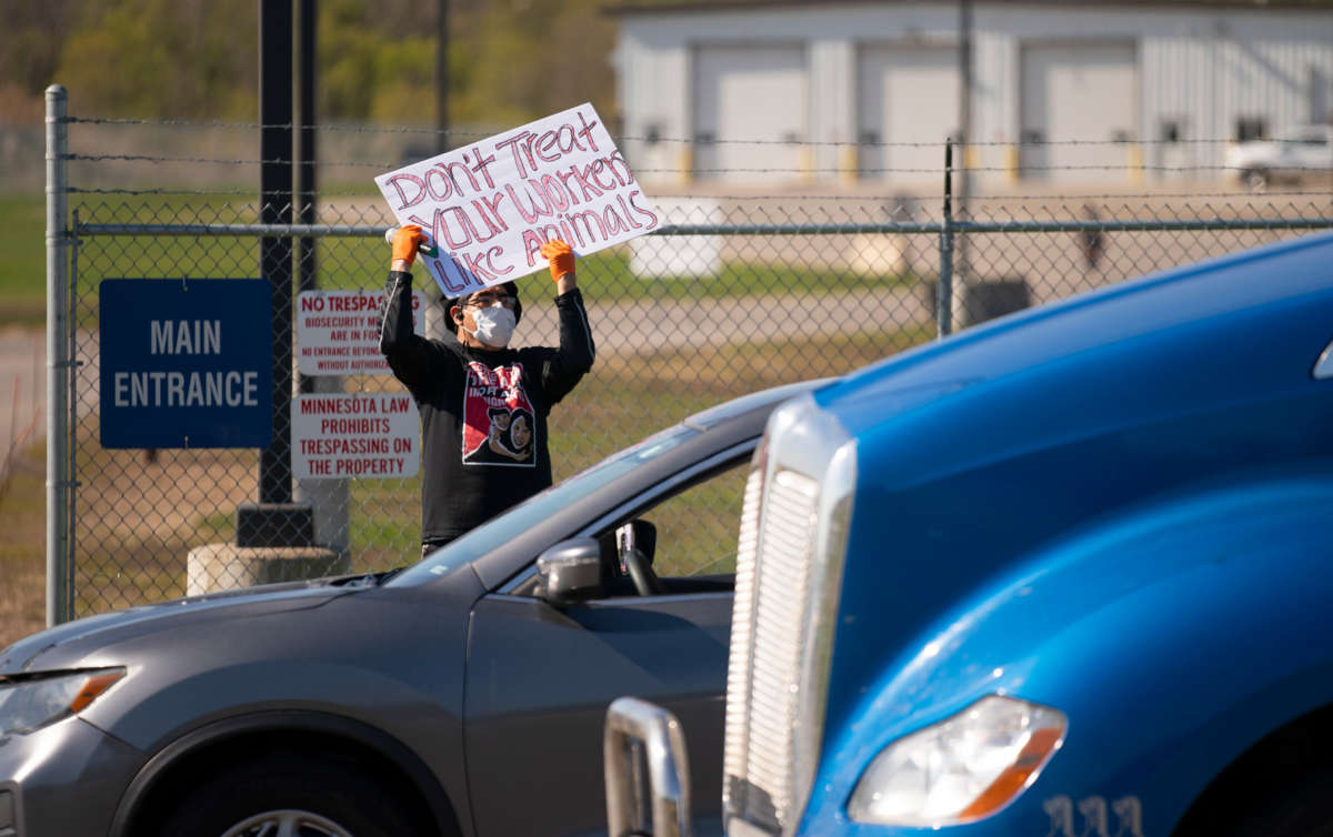 A protester holds a sign at the main entrance to the Pilgrim's Pride plant during a demonstration against unsafe working conditions on May 11, 2020.