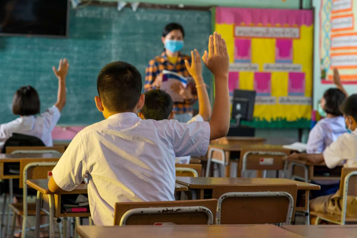 Students and their teacher wear protective face masks in classroom at elementary school after covid-19 quarantine and lockdown.