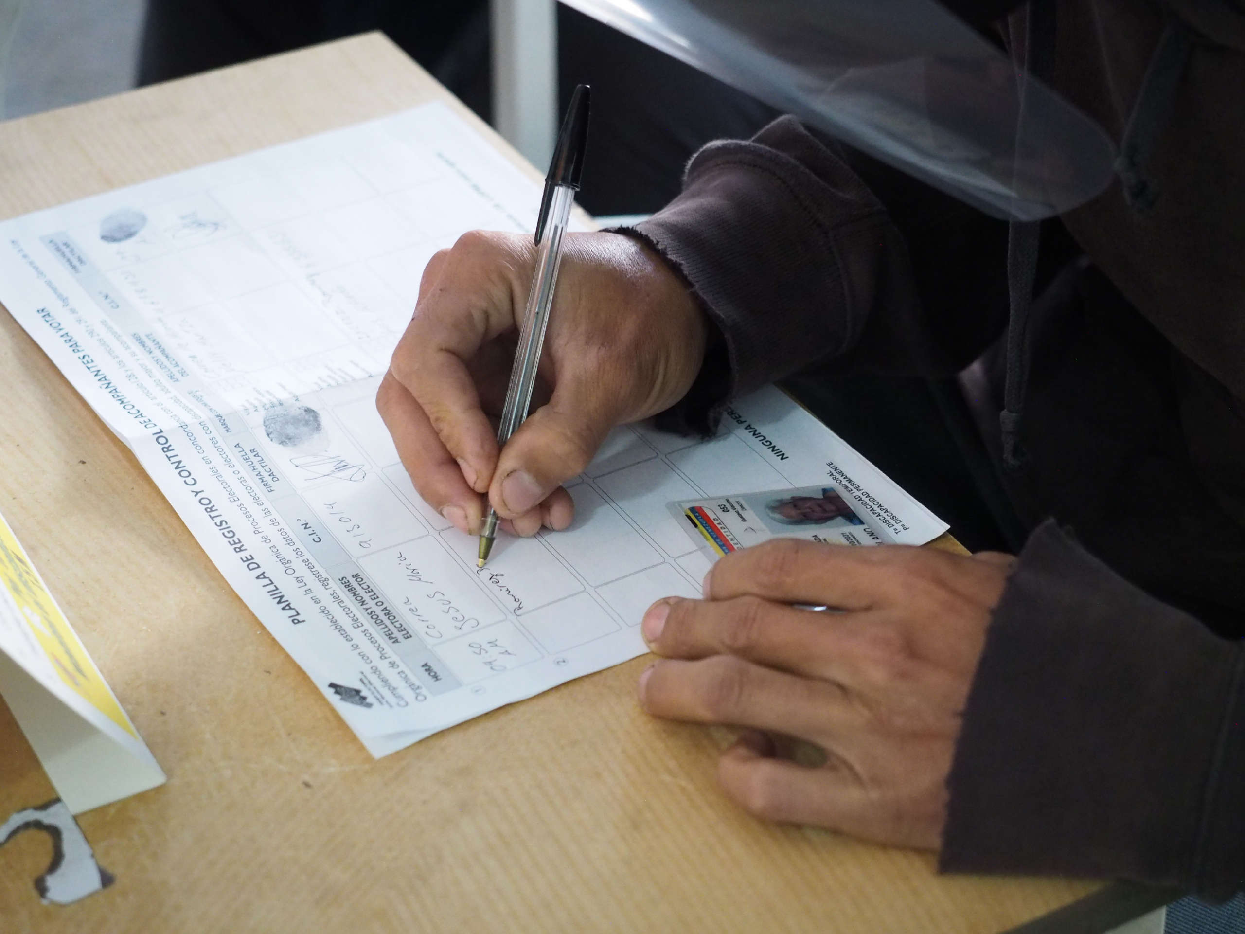 A worker notes a voter’s details as part of the voting process to prevent fraud at the Liceo Pedro Emilio Coll in the Coche Parish in Caracas, Venezuela during elections on November 21, 2021.