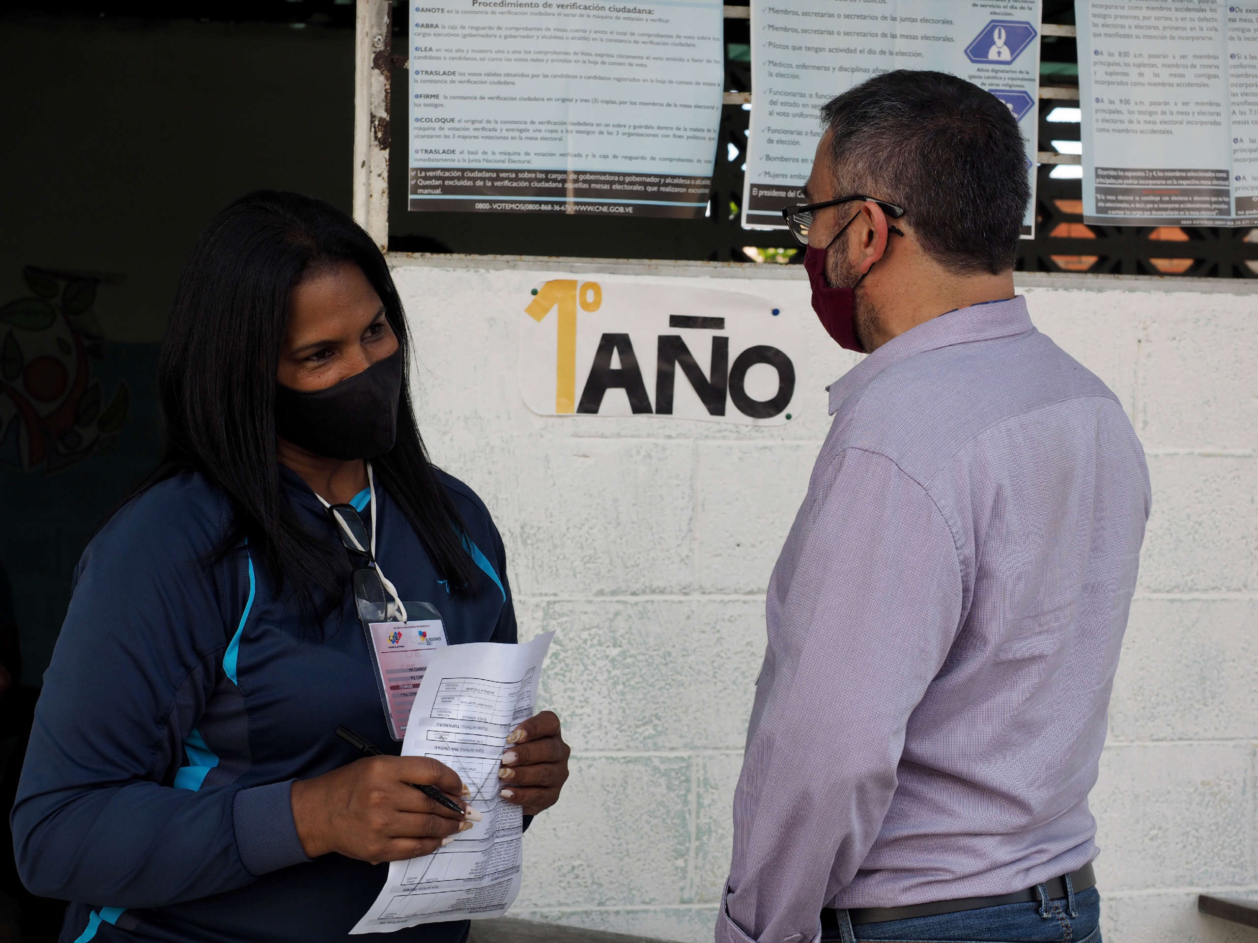 Election worker Cybel González talks with a Mexican election observer on November 21, 2021 at a voting location in Carrizal, Miranda, Venezuela.