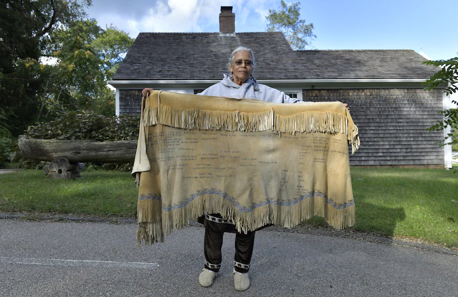 Anita Peters, a Mashpee Wampanoag who goes by her traditional name Mother Bear, holds a deerskin shawl that traces her ancestors back to 1580.