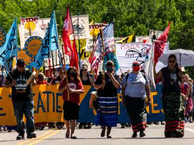 Climate activist and Indigenous community members hold a banner and flags during a rally and march against the Line 3 pipeline in Solway, Minnesota, on June 7, 2021.