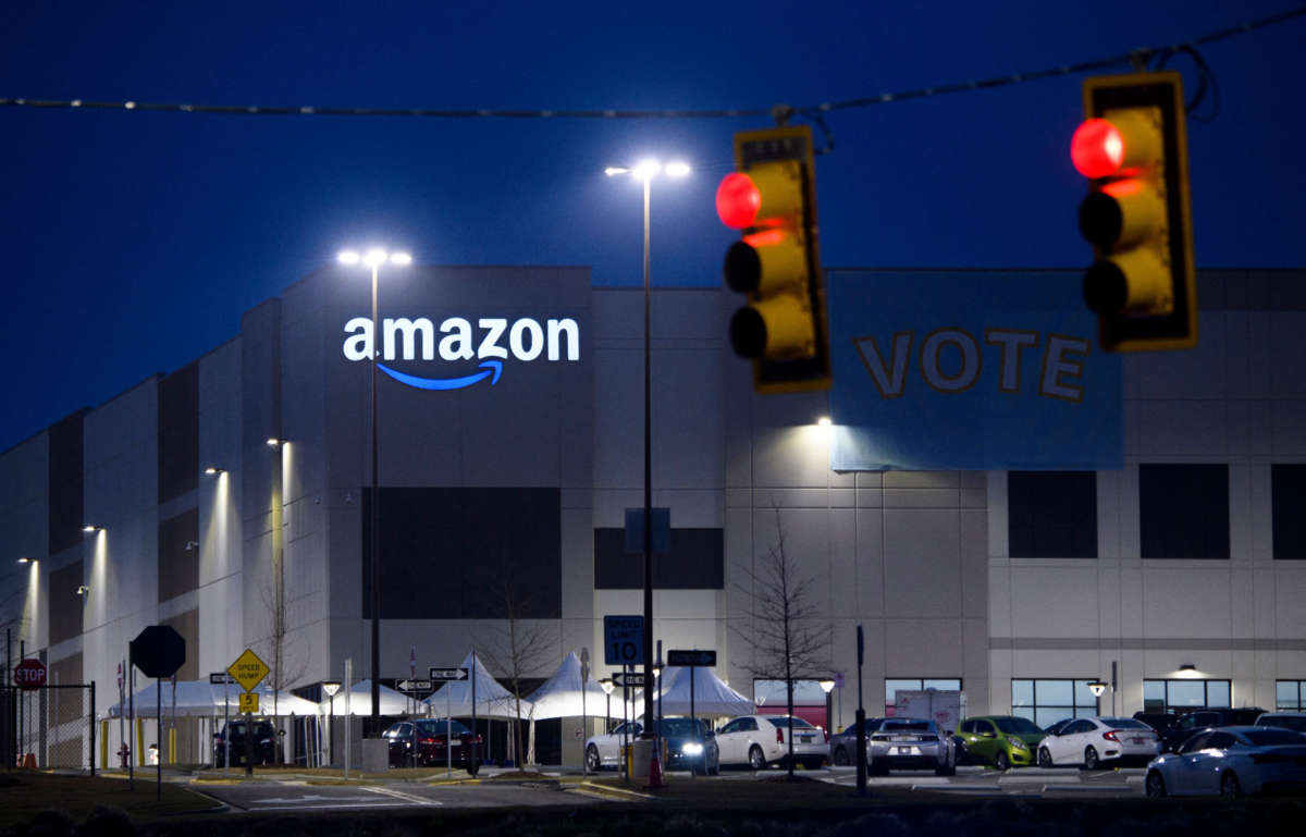 Amazon fulfillment center in Bessemer, Alabama, with banner reading Vote, seen past red stoplights