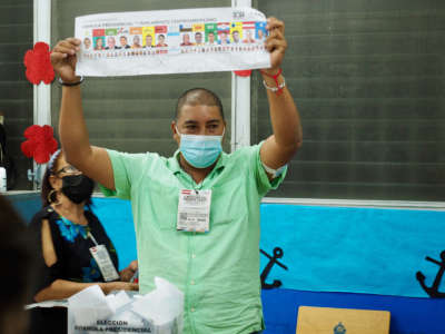 An election worker holds up a presidential ballot marking a preference for the LIBRE party as part of the vote counting process at the end of election day, Tegucigalpa