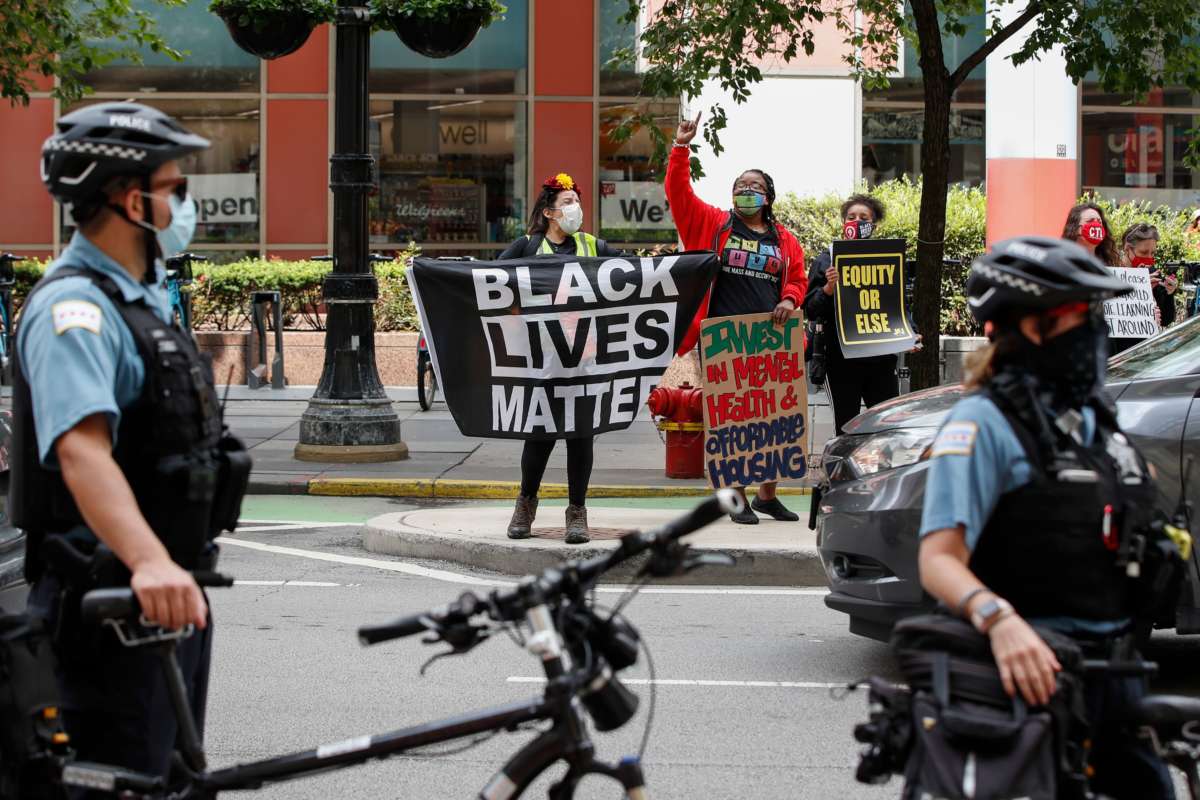 A woman holds a Black Lives Matter flag along with protesters holding signs during the Occupy City Hall Protest and Car Caravan hosted by Chicago Teachers Union in Chicago, Illinois, on August 3, 2020.