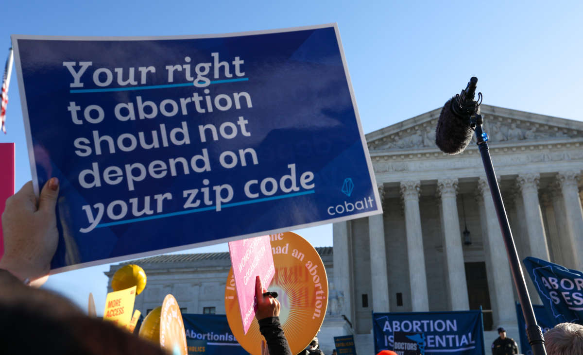 Abortion rights advocates demonstrate in front of the Supreme Court. A sign reads: Your right to abortion should not depend on your zip code.