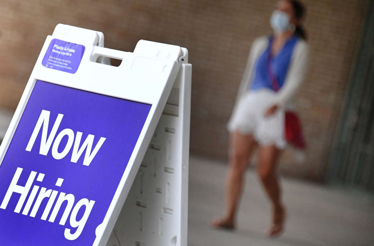 A pedestrian walks by a "Now Hiring" sign outside a store on August 16, 2021, in Arlington, Virginia.