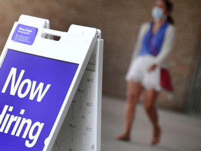 A pedestrian walks by a "Now Hiring" sign outside a store on August 16, 2021, in Arlington, Virginia.