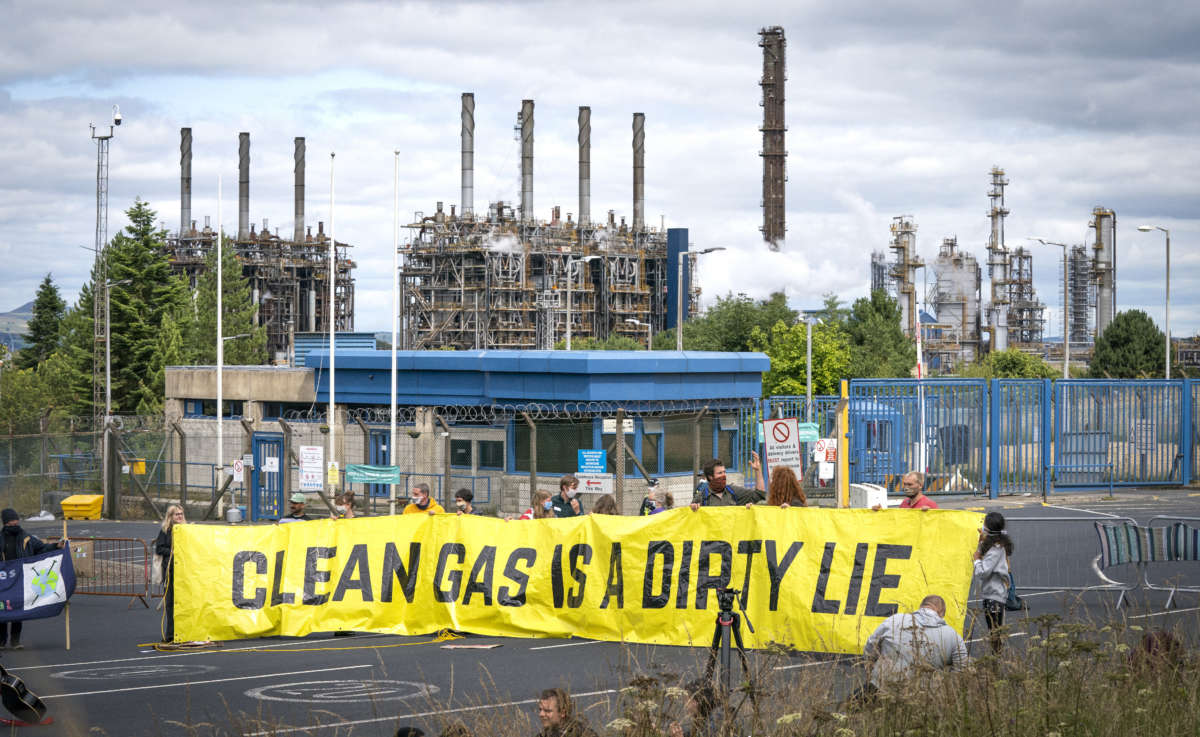 Climate activists demonstrate outside the gates of the Mossmorran petrochemical refinery near Cowdenbeath, Scotland, to protest against flaring and pollution at the plant on August 1, 2021.