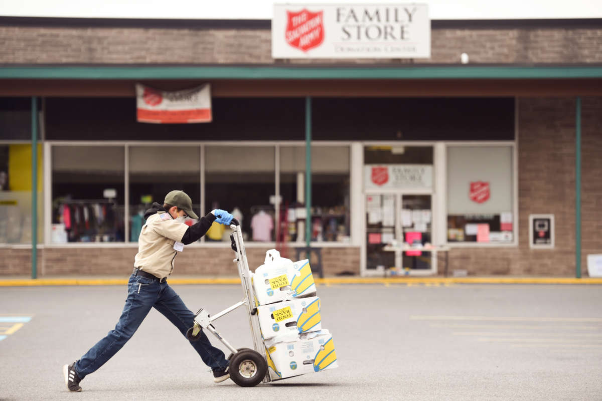 A youth wheels boxes of merchandise through a parking lot