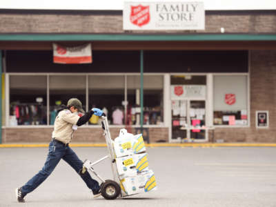 A youth wheels boxes of merchandise through a parking lot