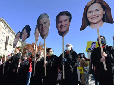 Protesters display cardboard cutouts of the faces of the United States Supreme Court justices